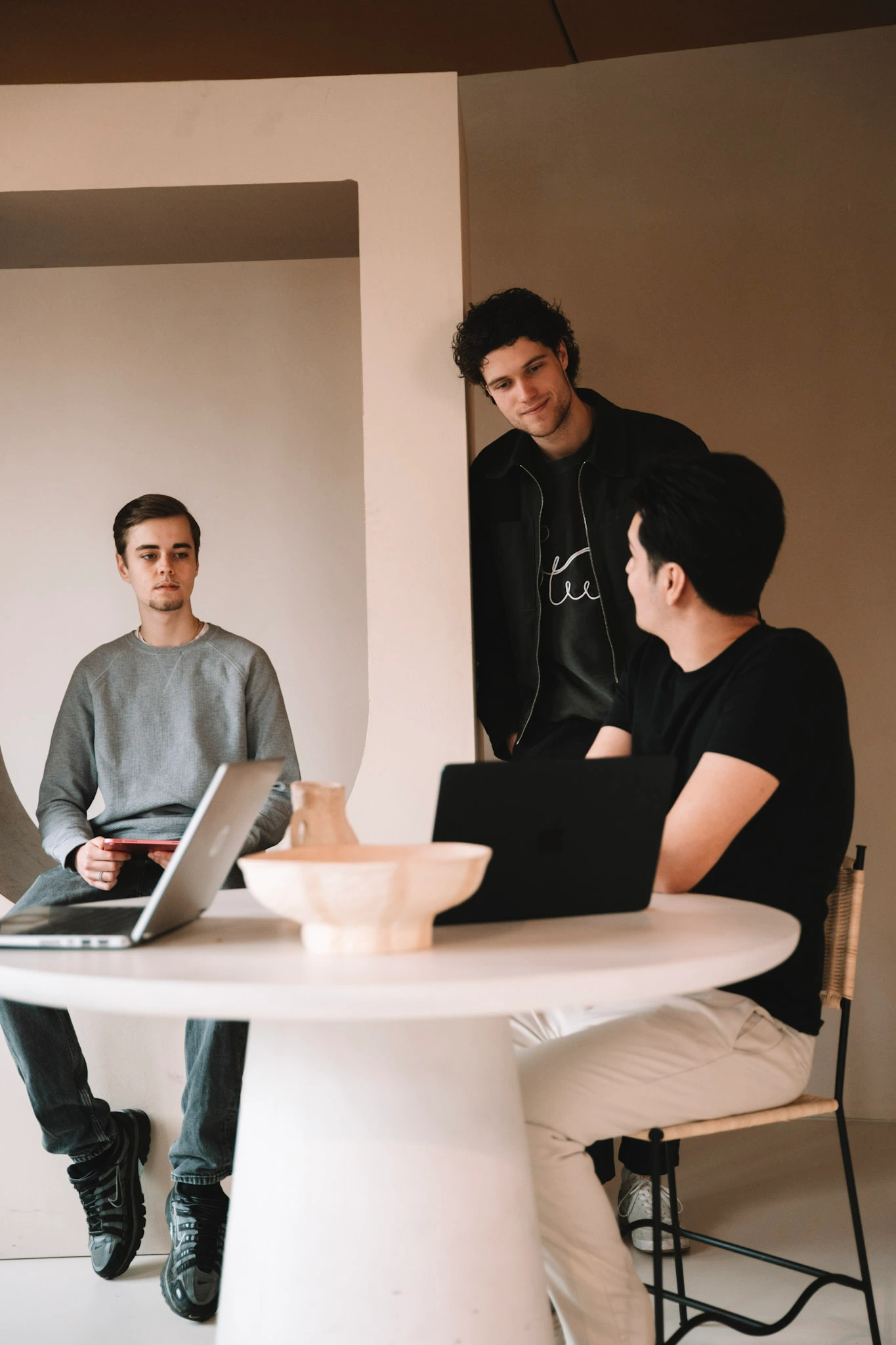 Drie teamleden van Veltman Marketing overleggen rond een tafel met een laptop
