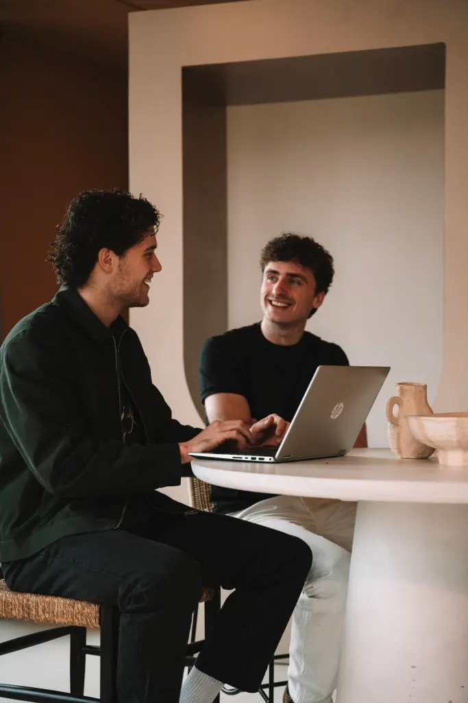 Twee teamleden van Veltman Marketing overleggen aan tafel met een laptop